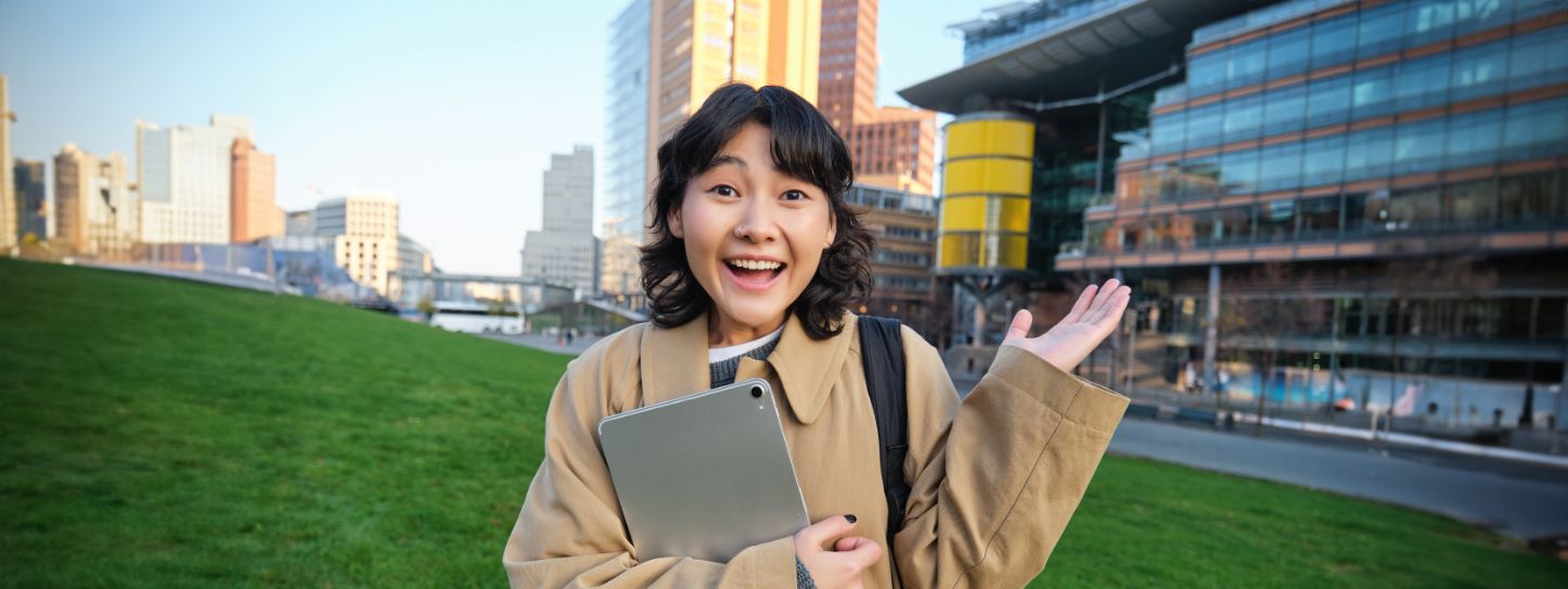 enthusiastic brunette asian girl student with digital tablet her hands looks impressed 1